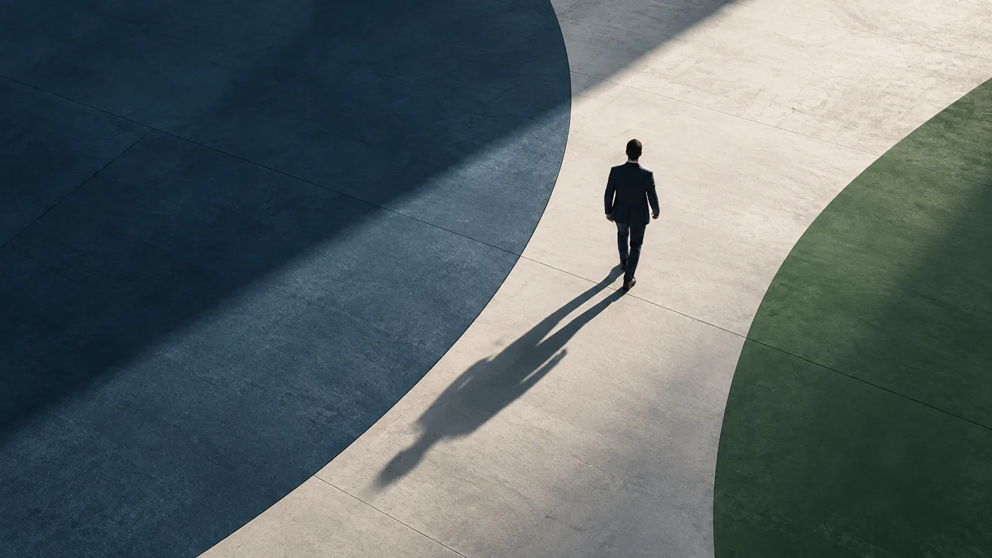 A lone figure walking a clear path between two large curved fields